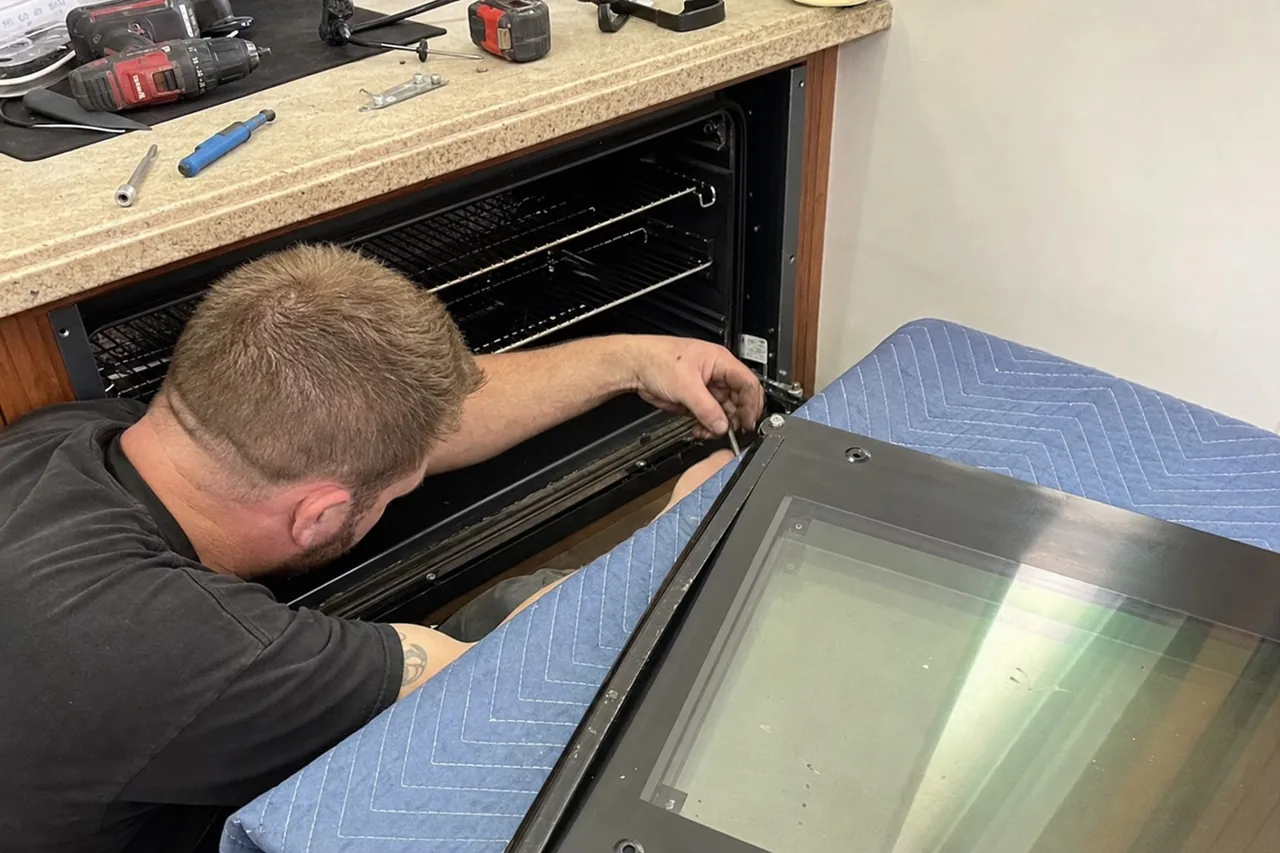 Mirrored view of an oven with its door off and the frame and rating-plate area exposed at the cavity edge